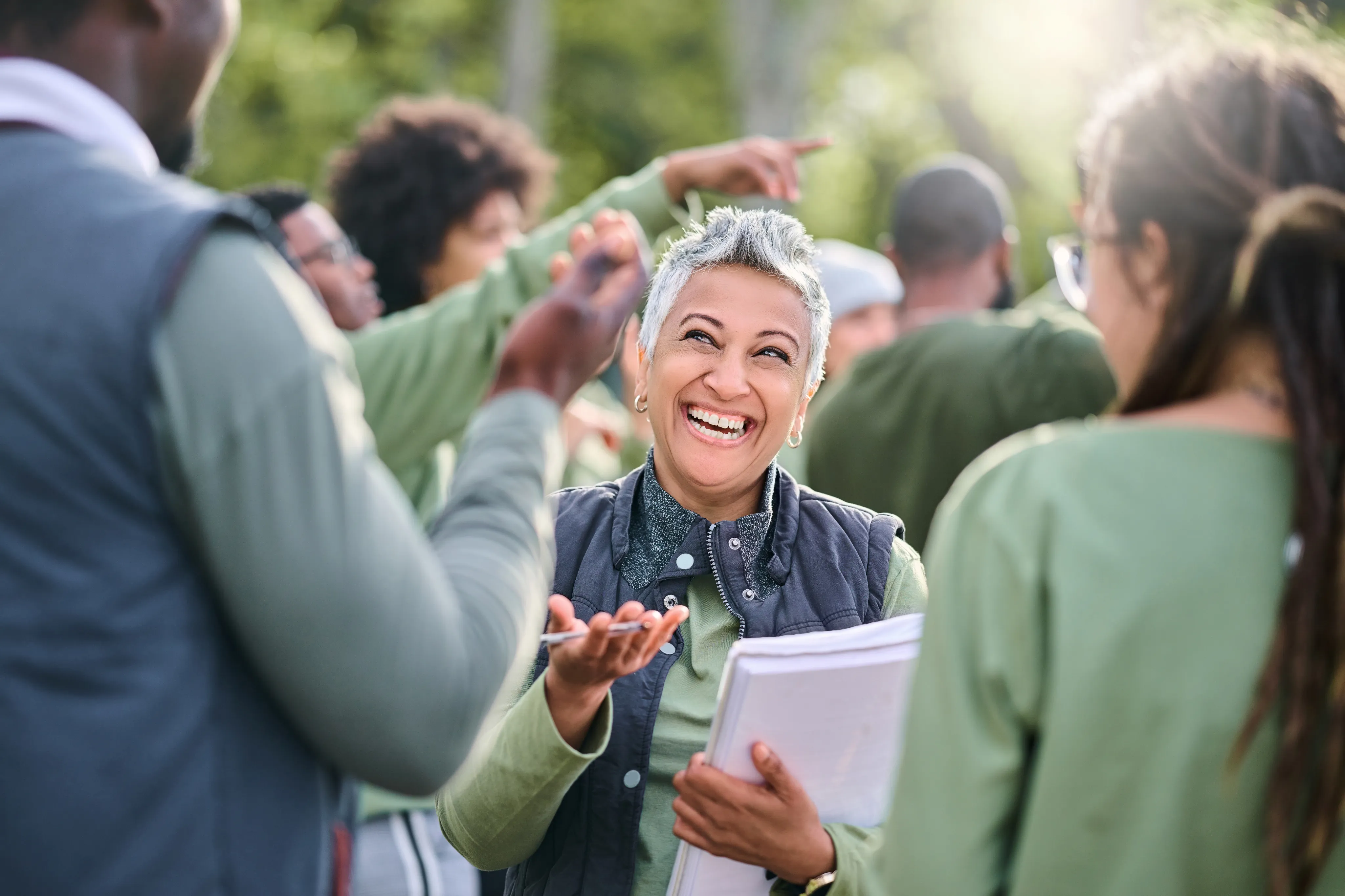 Happy woman in a crowd holding a sheaf of papers and a pen